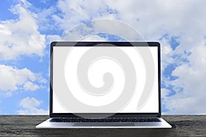 Laptop with white blank screen on wooden table and blue sky back