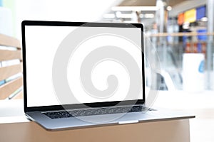 Laptop with white screen in business office or shopping mall. Empty copy space, blank screen mockup. Soft focus laptop