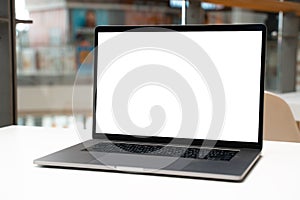 Laptop with white screen in business office or shopping mall. Empty copy space, blank screen mockup. Soft focus laptop