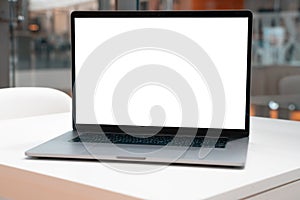 Laptop with white screen in business office or shopping mall. Empty copy space, blank screen mockup. Soft focus laptop