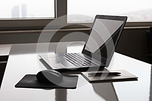 Laptop with white screen mock up template. Office desk with computer; coffee cup and pen