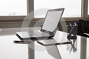 Laptop with white screen mock up template. Office desk with computer; coffee cup and pen