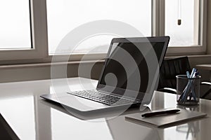 Laptop with white screen mock up template. Office desk with computer; coffee cup and pen