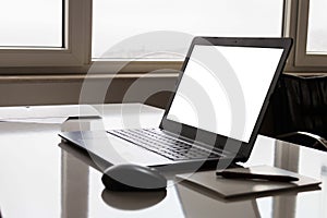 Laptop with white screen mock up template. Office desk with computer; coffee cup and pen