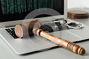 Laptop, wooden gavel and handcuffs on table, closeup. Cyber crime