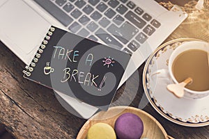 Laptop on wooden table with coffee and Take a break note