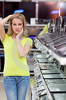 Beautiful girl in the department of laptops in the electronics store.