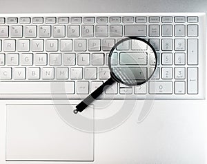 Laptops keyboard through magnifying glass. Internet search and keywording concept