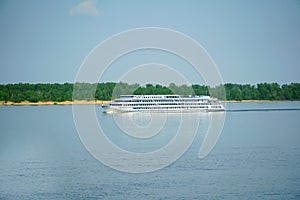 A large 4-deck cruise ship with tourists on board runs along the Volga upstream towards Moscow. Volgograd. Russia