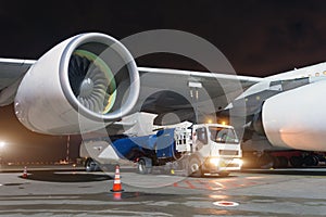 Large aircraft jet engines, Fueling a huge airplane, a truck with fuel with hoses connected to a fuel tank.