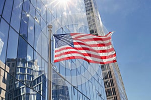 A large American flag waves in front of a reflective skyscraper