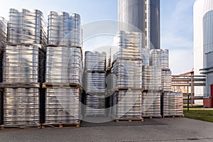 Large amount of aluminium beer kegs stacked on each other with euro palettes and wrapped around with vinyl foil