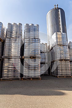 Large amount of aluminium beer kegs stacked on each other with euro palettes and wrapped around with vinyl foil