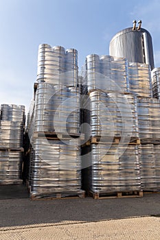 Large amount of aluminium beer kegs stacked on each other with euro palettes and wrapped around with vinyl foil