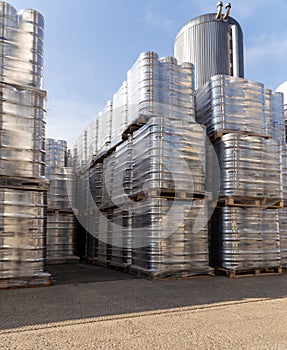 Large amount of aluminium beer kegs stacked on each other with euro palettes and wrapped around with vinyl foil