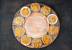 Large assortment of pasta on a round wooden tray. Top view, with space to copy.