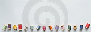 A large banner with lots of multicolored threads on wooden old-fashioned reels on a white background with space for text. One of