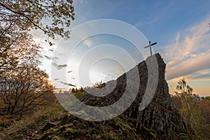 Basalt cone druid stone with summit cross with trees and sky photo