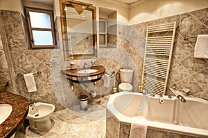 Large bathroom with toilet, bidet, pair of basins and bath