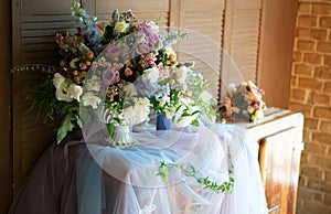 A large beautiful bright bouquet stands on an old chest of drawers in the bright morning sunlight