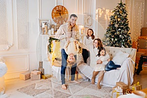 a large, beautiful and happy family in a room by the Christmas tree.