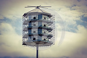 A Large bird house over a cloudy blue sky