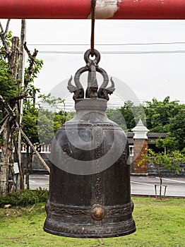 Large black ancient bell hanging on a steel beam.