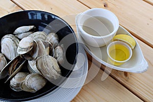 Large black bowl filled with fresh cooked steamers, melted butter on the side