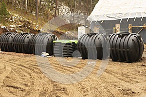 Large black plastic bins for waste disposal at a construction site.