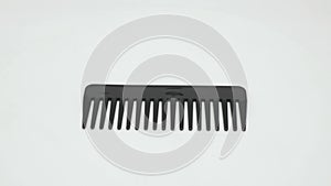 A large black plastic comb rotates on a white background.
