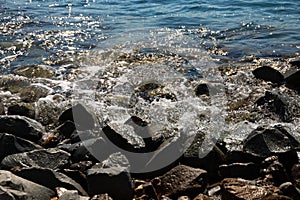 Large black stones on the Black Sea coast with waves crashing against them. Landscape