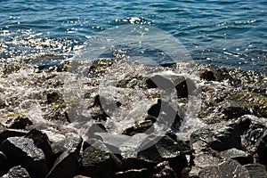 Large black stones on the Black Sea coast with waves crashing against them. Landscape