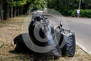 Large black trash bags filled with garbage are on the road. Clean area concept