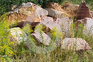 Large blocks of red granite with torn edges among grass