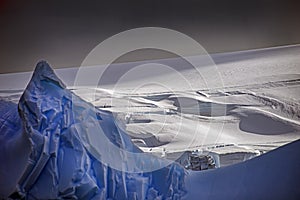 Large blue iceberg offshore of an ice cap covered landscape, Antarctica