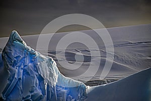 Large blue iceberg offshore of an ice cap covered landscape, Antarctica