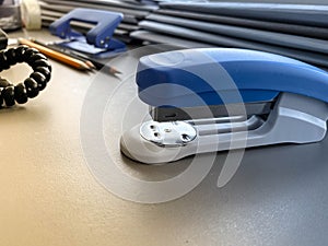 A large blue stapler for stapling paper lies next to the folders of documents on the working business desk in the office.