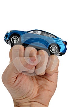 Large blue SUV car model placed on raised fist of adult man, white background.
