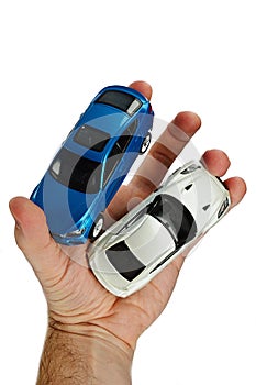 Large blue SUV and white supersport car models held in left palm of adult man, white background photo