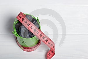 Large blueberries in a decorative bucket. Measuring tape for measuring the waist. International day without diets. Close-up