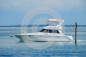 Large boat yacht cruising by channel marker