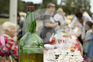 Large bottle of alcohol. Strong drink in green bottle. Festival on street