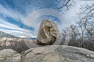 Large boulder of granite rock surounded by trees at Silla de Felipe II Phillip II chair in Guadarrama Mountains
