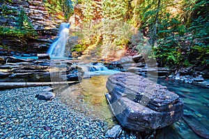 Large boulder in riverbed by blue majestic waterfall in canyon