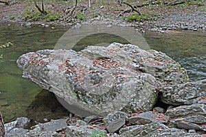 Large boulder on the side of a meandering stream