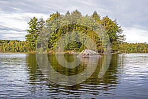 A Large Boulder Stands Before A Small Forested Island