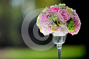 A large bouquet of flowers and colorful in a clear glass vase on a blurred green background