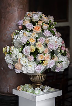 Large bouquet of roses in a vase on a marble pedestal