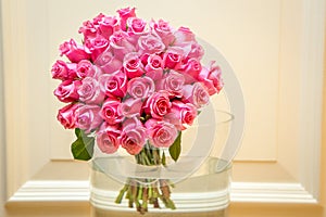 Large bouquet of two dozen pink roses in large glass vase