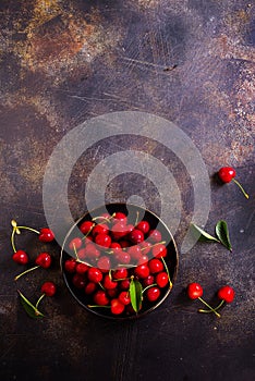 Large bowl of bright red cherries on dark background